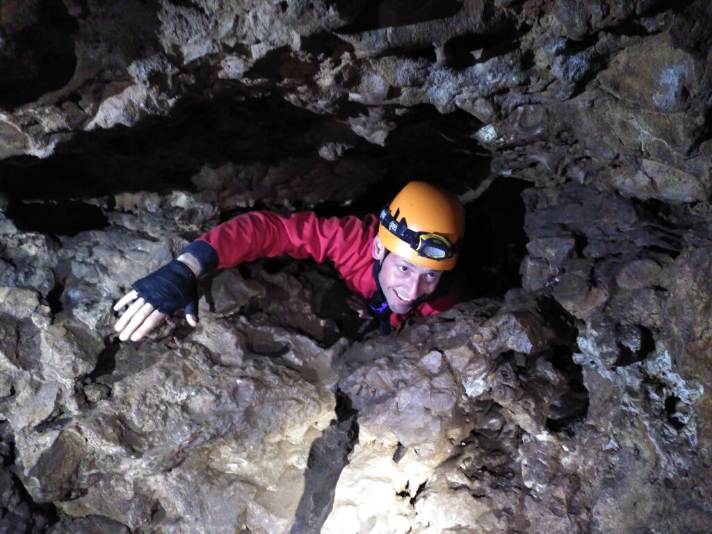 Man_squeezing_through_passage_in_cave